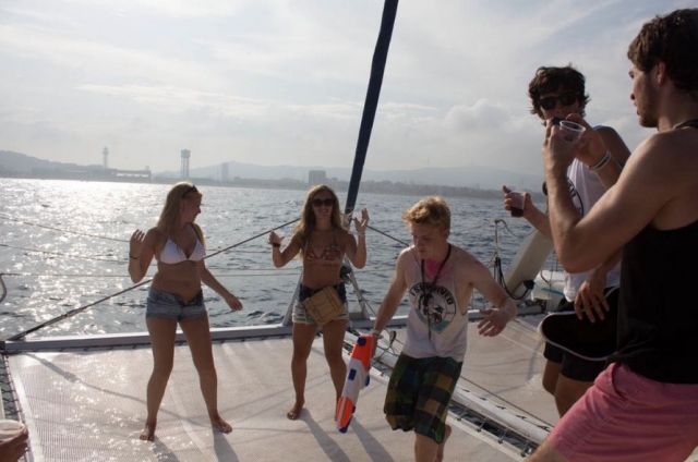 chico con una pistola de agua y otros bailando en el barco